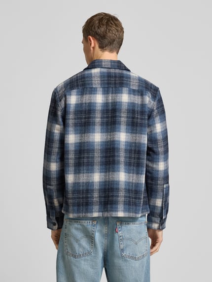 Männermodel trägt Hemdjacke mit Reißverschluss von MCNEAL, niebiesko-biała krata, materiał z domieszką wełny, widok całej sylwetki z tyłu.