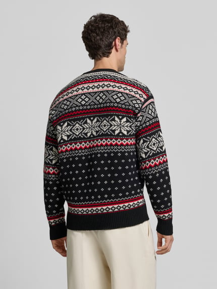 Männermodel trägt Pullover aus Wolle mit Wappenstickerei von POLO RALPH LAUREN, Strickoptik in Schwarz, Rot und Creme, geometrisches Muster, Ganzkörperansicht Rückansicht.