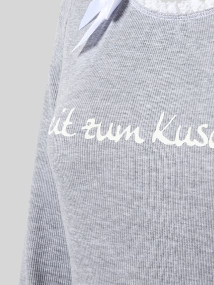 Vrouwenmodel draagt Nachthemd aus Baumwoll-Mix Modell 'Winterzauber' van LOUIS & LOUISA, grijze ribstructuur, statementprint, ruches, strikapplicatie, ronde hals, lang mouw, mix van katoen en elastaan, rechte fit, detailopname bovenlichaam.