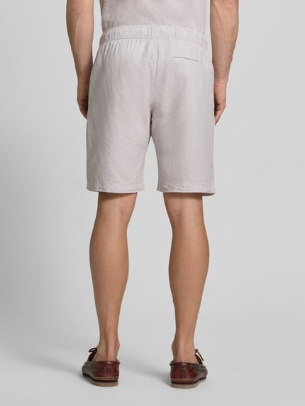 Männermodel trägt Shorts aus Leinen-Baumwoll-Mix mit elastischem Bund von MCNEAL in hellem Beige, Regular-Fit, Ganzkörperansicht Rückansicht. Kontext: Herren Shorts, Tunnelzug, Bundweite bei Größe M 44 cm, Innenbeinlänge bei Größe M 23 cm.