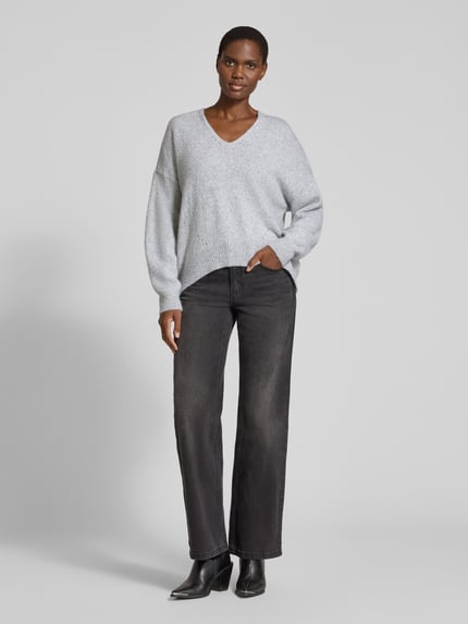 Frauenmodel trägt grauen Loose Fit Pullover aus Alpaka-Woll-Mix Modell 'Fondyssa' von BOSS Orange, kombiniert mit dunkler Hose, Ganzkörperansicht von vorne.