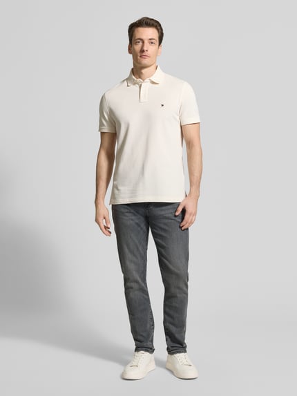 Männermodel draagt Slim Fit Jeans aus Baumwoll-Mix Modell 'BLEECKER' van Tommy Hilfiger in denimlook met labelpatch, riemlussen, knoop- en ritssluiting, 5-pocketmodel, katoenmix materiaal. Ganzkörperansicht van voren.