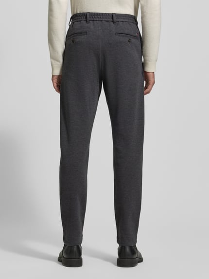 Männermodel trägt Relaxed Fit Schmale Hose aus reiner Baumwolle Modell 'HARLEM' von Tommy Hilfiger in Two-Tone-Optik, Regular-Länge, Label-Stitching, elastischer Bund, seitliche Eingrifftaschen, Gesäßtaschen, Knopf und verdeckter Reißverschluss, Ganzkörperansicht Rückansicht.