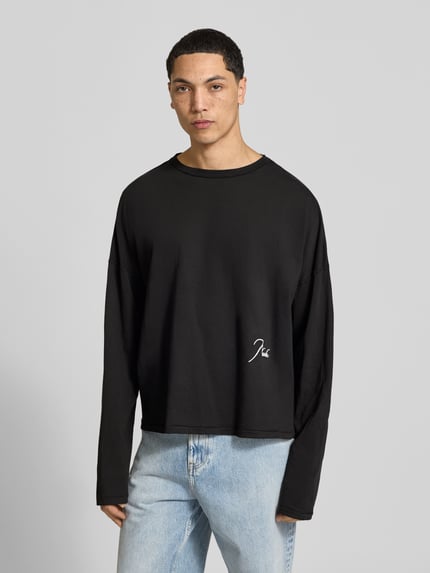Männermodel trägt Regular Fit Longsleeve aus katoen van RHUDE in zwart met labelstitchings, ronde hals, langmouwen, ruglengte maat M 62 cm, Ganzkörperansicht van voren