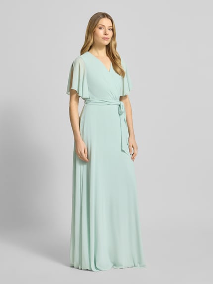 Frauenmodel trägt Regular Fit Abendkleid mit V-Ausschnitt von Christian Berg Cocktail in Hellgrün, Wickel-Optik, tailliert, mit Stoffband, ganzkörperansicht von vorne.