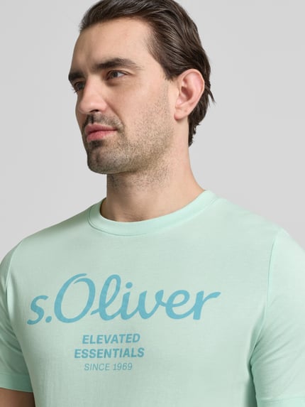 Mannenmodel draagt Regular Fit T-Shirt aus reiner Baumwolle van s.Oliver RED LABEL in uni mintgroen met labelprint, ronde hals, korte mouw, jersey van puur katoen, Nahaufnahme bovenlichaam.