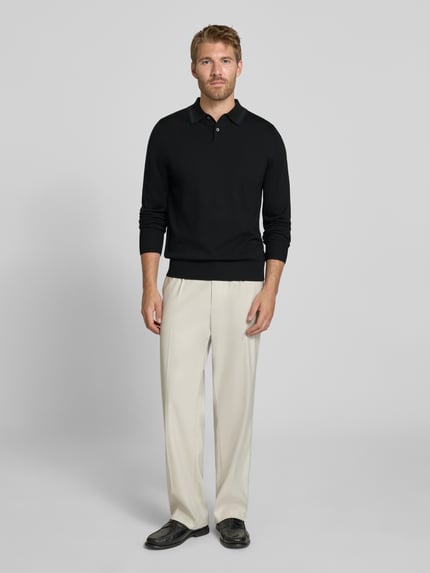 Männermodel trägt Regular Fit Poloshirt in Strick-Optik von Paul Smith in Schwarz, reine Wolle, Langarm, Polokragen, Label-Stitching, gerippte Abschlüsse, Rückenlänge 67 cm, Ganzkörperansicht von vorne.