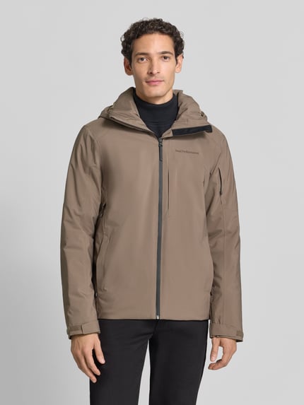 Männermodel trägt Regular Fit Jacke mit Kapuze Modell 'Maroon' von Peak Performance in Braun, Reißverschluss, Label-Stitching, Ganzkörperansicht von vorne.