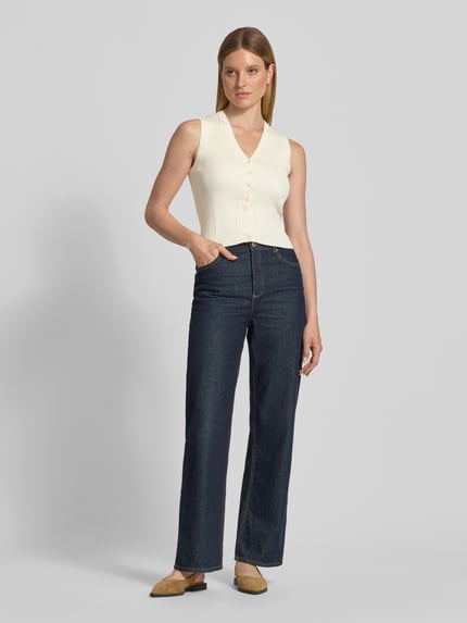 Frauenmodel trägt Strickweste aus Viskose-Mix mit V-Ausschnitt von Jake*s, Slim-Fit, Ripp-Optik, Knopfleiste, Rückenlänge 50 cm, Ganzkörperansicht von vorne.