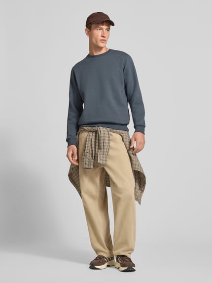 Männermodel trägt Regular Fit Sweatshirt mit Baumwoll-Anteil Modell 'Bradley' von JACK & JONES in Blau, Ganzkörperansicht von vorne. Material-Mix, Rundhalsausschnitt, Langarm, gerippte Abschlüsse, Logo-Label sichtbar.