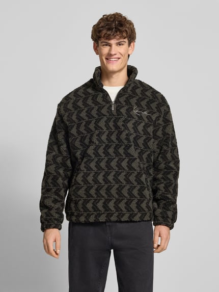 Männermodel trägt Fleecepullover mit Stehkragen und Reißverschluss von KARL KANI im Allover-Look, Regular-Fit, Logo, Ganzkörperansicht von vorne.
