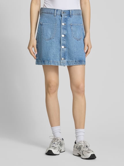 Vrouwenmodel draagt Schmaler Jeansrock aus reiner Baumwolle Modell 'AMAZING' van Only, denimlook, contrastnaad, riemlussen, knoopsluiting, opgestikte zakken, smal pasvorm, minilengte, puur katoen, ganzkörperansicht van voren.