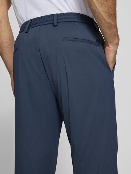Männermodel trägt Regular Fit Hose mit Tunnelzug und Eingrifftaschen von bugatti in Dunkelblau, Material-Mix, Nahaufnahme Rückansicht.