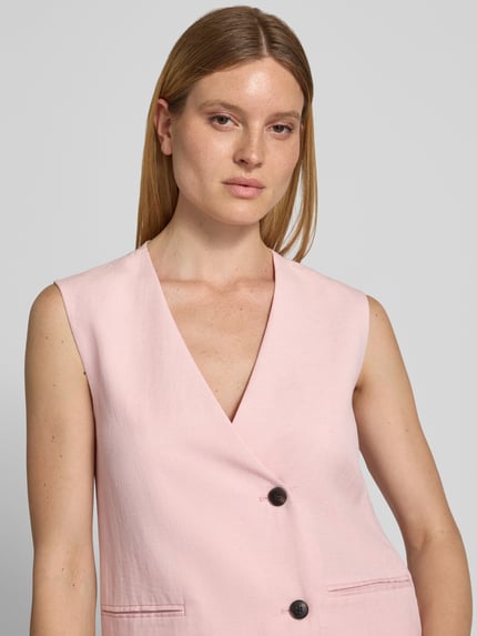 Frauenmodel trägt Oversized Weste aus Viskose-Lyocell-Mix Modell 'Franciska' von MSCH Copenhagen, zartrosa, leicht strukturierte Oberfläche, 2-Knopfleiste, Paspeltaschen, Nahaufnahme Oberkörper. Rückenlänge bei Größe S: 69 cm, Schulterbreite: 39 cm, Brustweite: 46 cm, Leinen-Anteil.