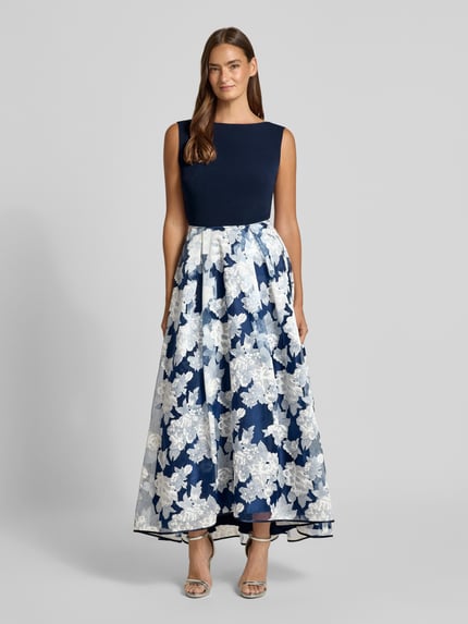 Frauenmodel trägt Abendkleid mit rückseitigem V-Ausschnitt von Christian Berg Cocktail, dunkelblau, florales Muster, Material-Mix mit Viskose-Anteil, Taillierter Schnitt, Midikleid, U-Boot-Ausschnitt, Rückenreißverschluss, verlängerter Saum hinten, Rückenlänge 131 cm, Brustweite 43 cm, Ganzkörperansicht von vorne.