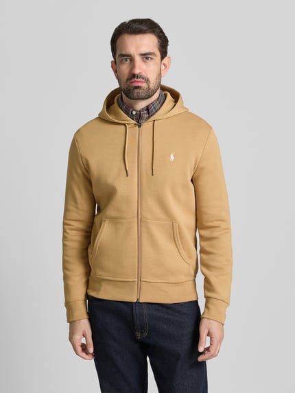 Männermodel trägt Sweatjacke mit Kapuze von Polo Ralph Lauren, Regular-Fit, Baumwoll-Elasthan-Mix, Reißverschluss, Eingrifftaschen, Label-Stitching, gerippte Abschlüsse, Kapuze mit Tunnelzug, Farbe beige, Rückenlänge 68 cm, Ärmellänge 65 cm, Ganzkörperansicht von vorne.