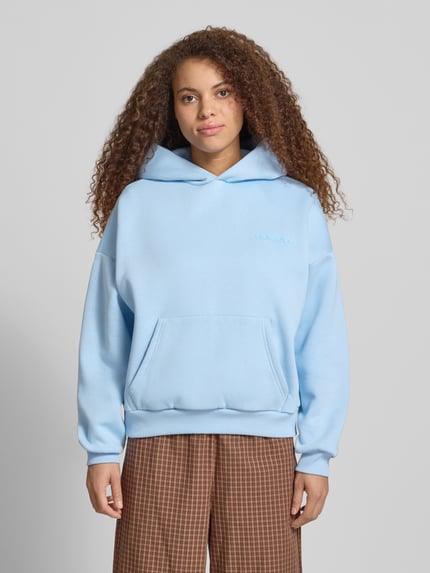 Frauenmodel trägt Hoodie mit Logo-Print und Känguru-Tasche von REVIEW aus Baumwoll-Mix, Loose-Fit, Kapuze, Ganzkörperansicht von vorne.