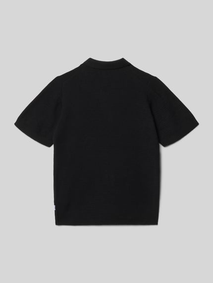Vrouwenmodel draagt Regular Fit Poloshirt in Strick-Optik Modell 'Max' van Jack & Jones, zwart, katoen, kort. Achteraanzicht, Ganzkörperansicht.