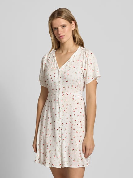 Modelka kobieca ma na sobie Minikleid aus reiner Viskose Modell 'EVIDA' od Only, kremowy z kolorowym wzorem, pasek w talii, krótki rękaw, krój slim fit, mini, dekolt V, czysta wiskoza, ujęcie całej sylwetki z przodu.