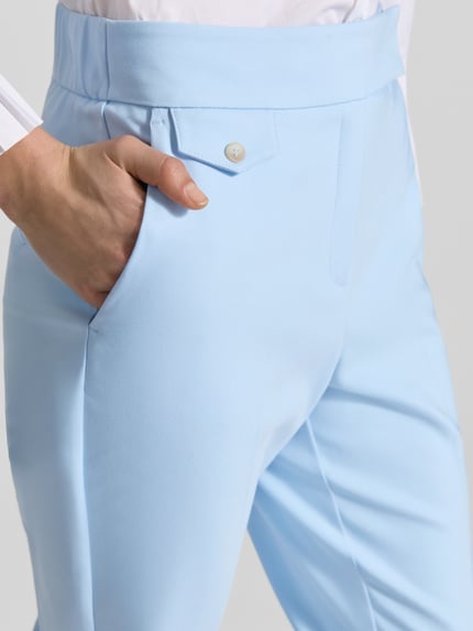 Frauenmodel trägt Regular Fit Stoffhose mit Baumwoll-Anteil von s.Oliver BLACK LABEL in Optik: Unifarben, Nahaufnahme Hüfte. Passform: Regular Fit, Details: Bügelfalten, Verschluss: Schiebehaken und verdeckter Reißverschluss, Bundabschluss: elastisch, seitliche Eingrifftaschen, angedeutete Münztasche und Gesäßtaschen.