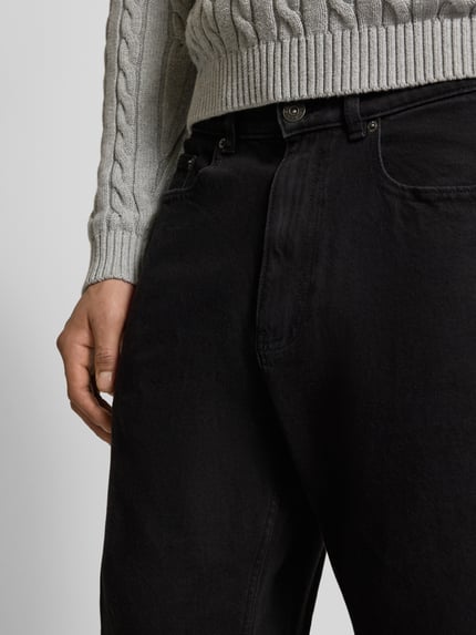 Männermodel trägt Baggy Fit Jeans mit Knopfverschluss von REVIEW in Schwarz, 5-Pocket-Design, Nahaufnahme Oberkörper