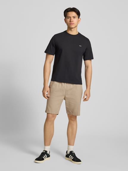 Męski model nosi Straight Fit Shorts mit Gesäßtasche od REVIEW, bawełna, len, elastyczny pas, beżowy kolor, pełny widok z przodu