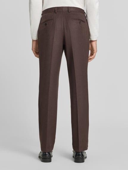 Männermodel trägt Anzughose mit Bügelfalte und Eingrifftaschen von Christian Berg Men in Braun, Material-Mix, Straight Fit, Ganzkörperansicht Rückansicht.