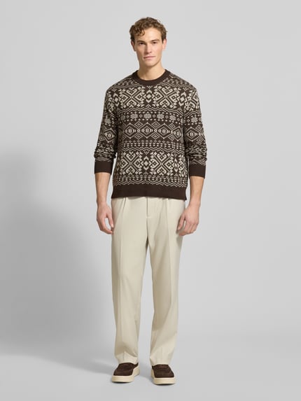 Männermodel trägt Regular Fit Strickpullover aus Woll-Mix Modell 'HOLGER' von SELECTED HOMME mit Jacquard-Muster und Rundhalsausschnitt, Ganzkörperansicht von vorne.