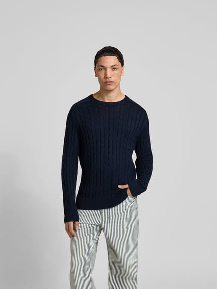 Męski model nosi Slim Fit Pullover in Strick-Optik od Filippa K z czystej bawełny, krój slim fit, okrągły dekolt, elastyczne wykończenia, długość tyłu w rozmiarze M: 69 cm, granatowy sweter o teksturze dzianiny, widok całej sylwetki z przodu.
