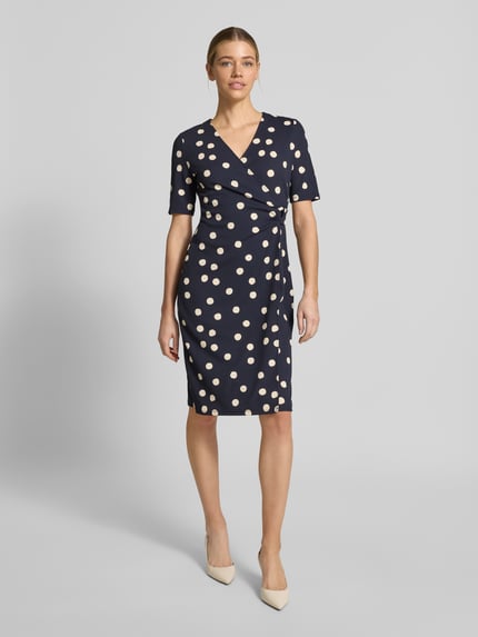 Frauenmodel trägt Tailliertes Midikleid in Wickeloptik von s.Oliver BLACK LABEL mit Optik:Allover-Muster, Muster: Polka-Dots, O-Ring, V-Ausschnitt, Ärmelform: Kurzarm, Midi-Länge, Ganzkörperansicht von vorne.