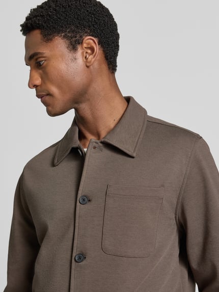 Männermodel trägt Slim Fit Hemdjacke mit Viskose-Anteil von Lindbergh in Braun, sichtbare Brusttasche und Umlegekragen, Nahaufnahme Oberkörper. Elastischer Material-Mix, durchgehende Knopfleiste.