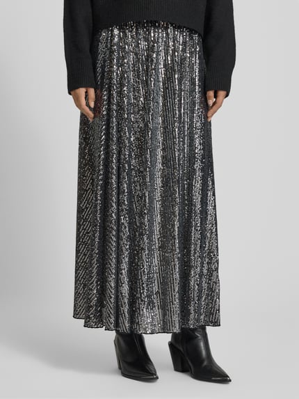 Frauenmodel trägt Maxirock mit Paillettenbesatz von Rich & Royal, silber-schwarzer Material-Mix, lockerer Schnitt, blickdichter Unterrock, Nahaufnahme Unterkörper.