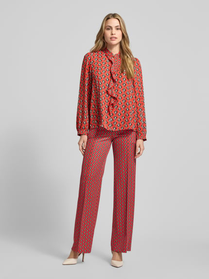 Frauenmodel trägt Regular Fit Bluse im Allover-Look mit Volants von Marc Cain in Rot mit Muster, Stehkragen, Schlüsselloch-Ausschnitt, Ganzkörperansicht von vorne.