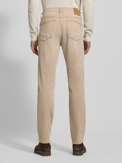 Męski model nosi Slim Fit Jeans mit 5-Pocket-Design Modell 'Chuck' od Brax, beżowy bawełniano-elastanowy materiał, widok całej sylwetki z tyłu.