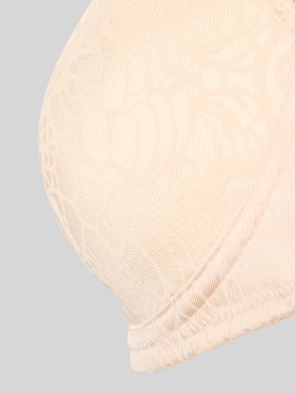 Frauenmodel trägt BH mit Hakenverschluss von Triumph, beige, florale Struktur, Material-Mix mit Stretch-Anteil, Nahaufnahme Oberkörper.