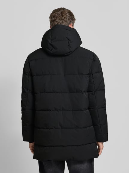 Männermodel trägt Steppmantel mit Zweiwege-Reißverschluss Modell 'COMFORT' von CINQUE in Schwarz, gerippte Ärmelabschlüsse, Ganzkörperansicht Rückansicht. Bei diesem Design von CINQUE erkennt man Kapuze, Label-Patch, seitliche Reißverschlusstaschen, Straight Fit und dezente Steppstruktur.