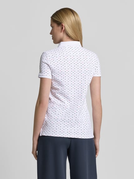Vrouwenmodel draagt Slim Fit Poloshirt met katoen van Christian Berg Woman, kort mouwontwerp, witte stof met kleine stippen, rugaanzicht, context: polokraag, katoen-elastaan-mix, ruglengte maat S 61 cm.