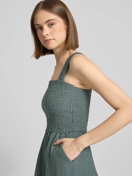 Frauenmodel trägt Regular Fit Jumpsuit mit gesmoktem Rumpf Modell 'ELISE' von Only in Optik: Unifarben mit Karree-Ausschnitt, breite Träger, ohne Ärmel und Eingrifftaschen, Nahaufnahme Oberkörper.