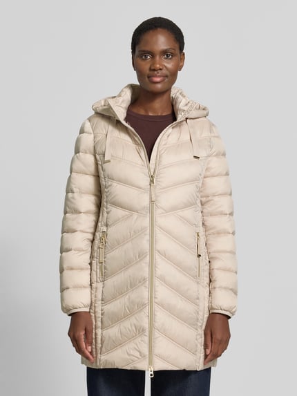 Modelka kobieca nosi Steppmantel mit Zweiwege-Reißverschluss von Christian Berg Woman Selection, beżowy, krój slim fit, kaptur z troczkiem, kieszenie na zamek, długość pleców w rozmiarze 36: 83 cm, szerokość ramion w rozmiarze 36: 40 cm, szerokość klatki piersiowej w rozmiarze 36: 48 cm, długość rękawa w rozmiarze 36: 65 cm, ujęcie całej sylwetki z przodu.