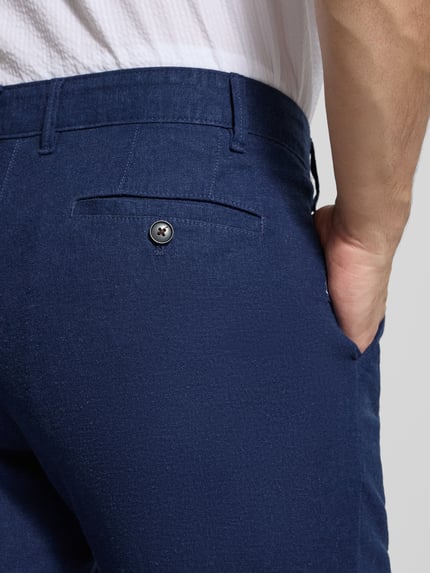 Männermodel trägt Hose aus Leinen-Viskose-Mix mit Eingrifftaschen von Christian Berg Men, Regular-Fit, Knopf- und Reißverschluss, Nahaufnahme Rückenansicht, Farbe Dunkelblau, spürbar glatte Textur, Bundweite bei Größe 50: 47 cm, Innenbeinlänge: 78 cm.