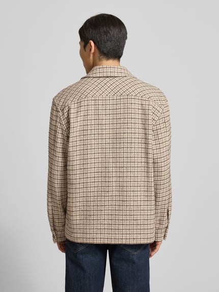 Męski model nosi Oversized Hemdjacke aus Woll-Mix Modell 'REGARI' od SELECTED HOMME w beżowo-czarny wzór pepitka, widok całej sylwetki z tyłu.