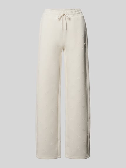 Produktfoto, jasnobeżowe szerokie spodnie dresowe z elastycznego materiału, allover-logo, model 'Calista' od Guess Activewear, szerokość w rozmiarze S: 80 cm, szeroki krój