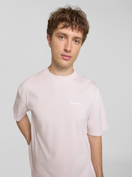 Männermodel trägt Oversized T-Shirt mit Label-Stitching von Pegador aus Baumwoll-Mix in Hellrosa, Rundhalsausschnitt, Nahaufnahme Oberkörper, Rückenlänge bei Größe M 70 cm.