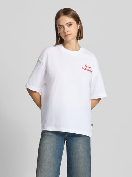 Frauenmodel trägt Relaxed Fit T-Shirt mit Label-Print Modell 'INTELLIGENT' von New Balance, reine Baumwolle, weiß, Ganzkörperansicht von vorne.