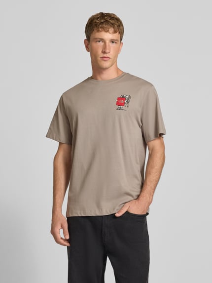 Männermodel trägt T-Shirt aus reiner Baumwolle Modell 'Gear Up Get Out' von The North Face in Beige mit Logo-Print, Ganzkörperansicht von vorne. Regular Fit, kurzärmliges Design und Rundhalsausschnitt sind im Kontext enthalten, Rückenlänge bei Größe M 68 cm.