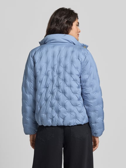 Frauenmodel trägt Regular Fit Daunenjacke mit Logo-Stitching von Tommy Hilfiger in Hellblau, gesteppte Struktur, Ganzkörperansicht Rückansicht, Damen Daunenjacke von Tommy Hilfiger.