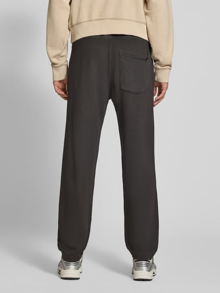 Männermodel trägt Relaxed Fit Sweathose aus reiner Baumwolle von G-Star RAW in Dunkelgrau, lockere Passform, Ganzkörperansicht Rückansicht.