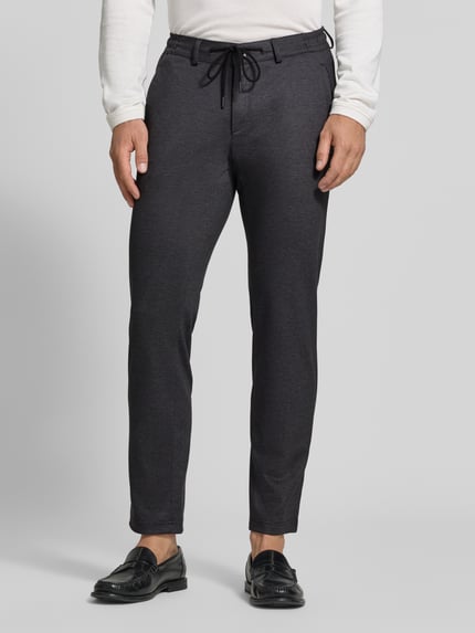 Männermodel trägt dunkelgraue Tapered Fit Jogpants mit Viskose-Anteil Modell 'Phil' von Brax, Herren Weite Hose, Ganzkörperansicht von vorne.