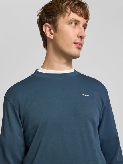 Männermodel trägt Langarmshirt mit kleinem Logo-Schriftzug von G-Star RAW in Unifarbe, strukturierte Jersey-Optik, Nahaufnahme Oberkörper.