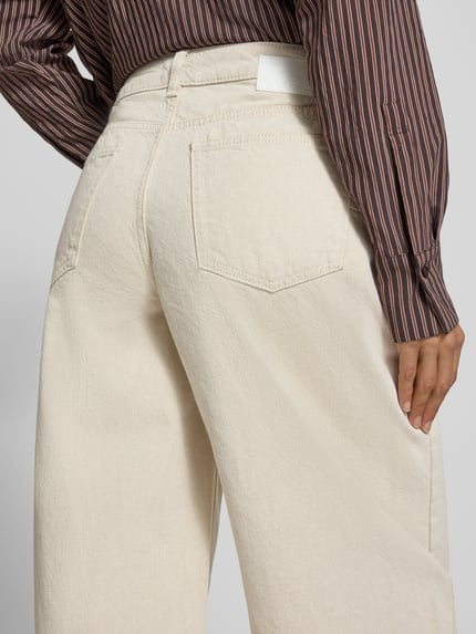 Frauenmodel trägt Regular Fit Barrel Jeans mit Bundfalte von OPUS, cremefarbener Denim mit Strukturmuster und Label-Patch, Nahaufnahme Rückansicht.